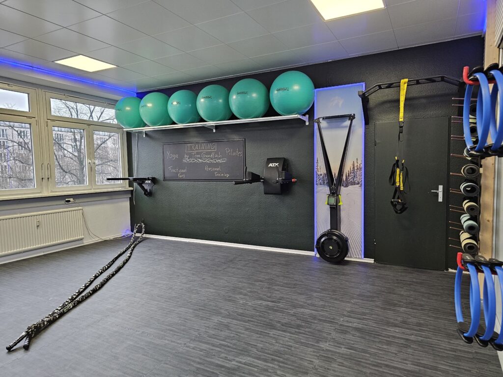 Kursraum der Therapiepraxis Tom Gundlach mit Gymnastikbällen, SkiErg, Schlingentrainer und Yogamatten
